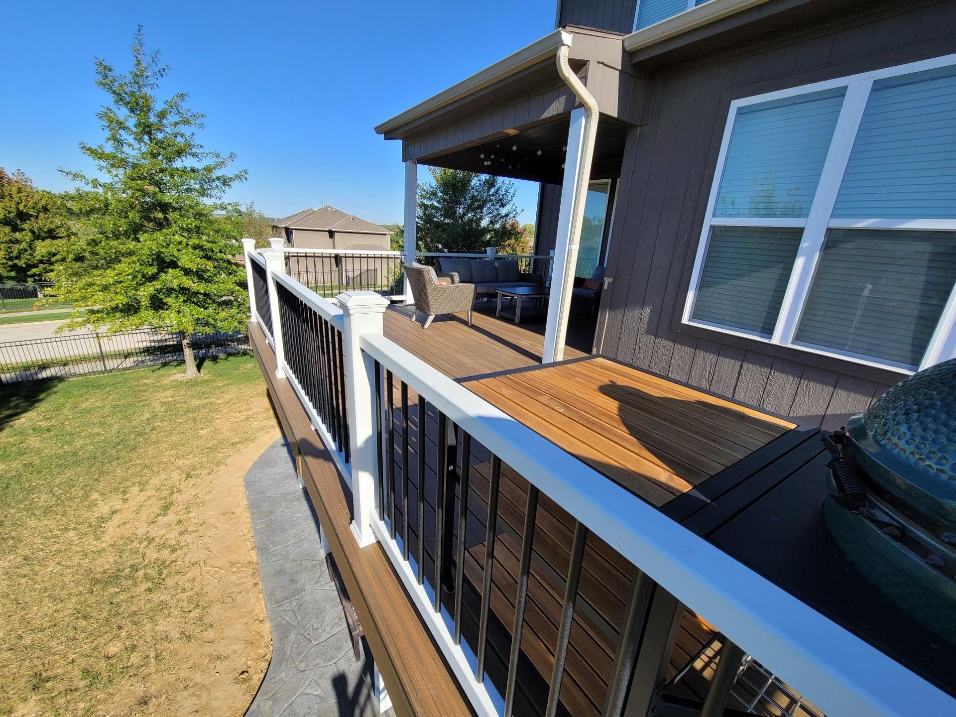 A wooden deck with a white railing is sitting on the side of a house.