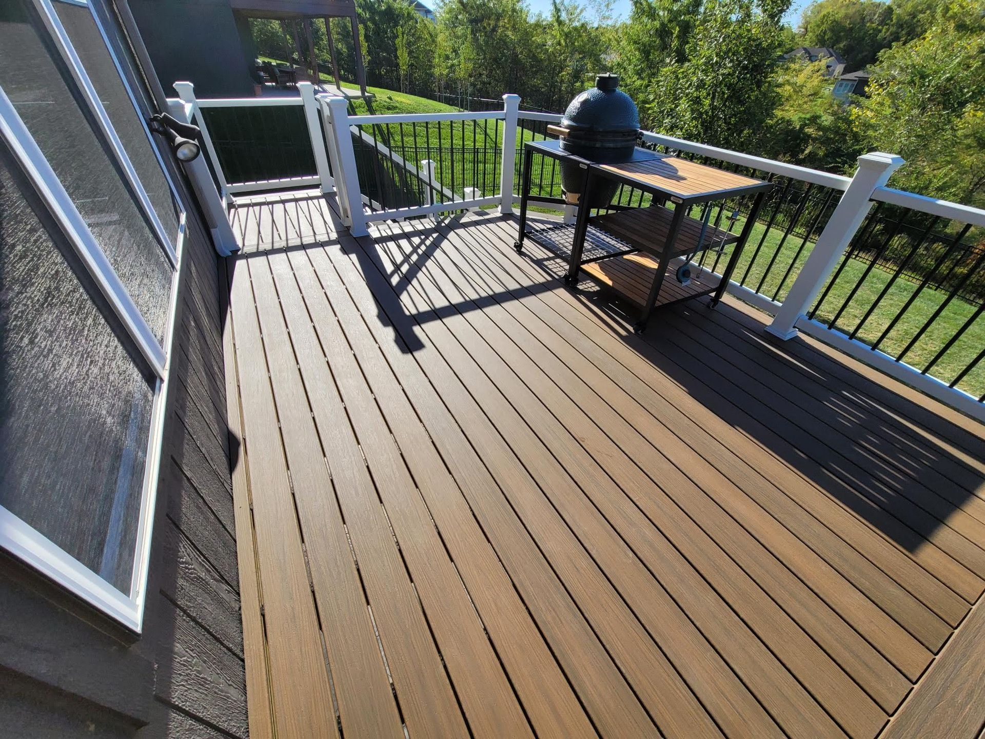 A wooden deck with a grill and chairs on it