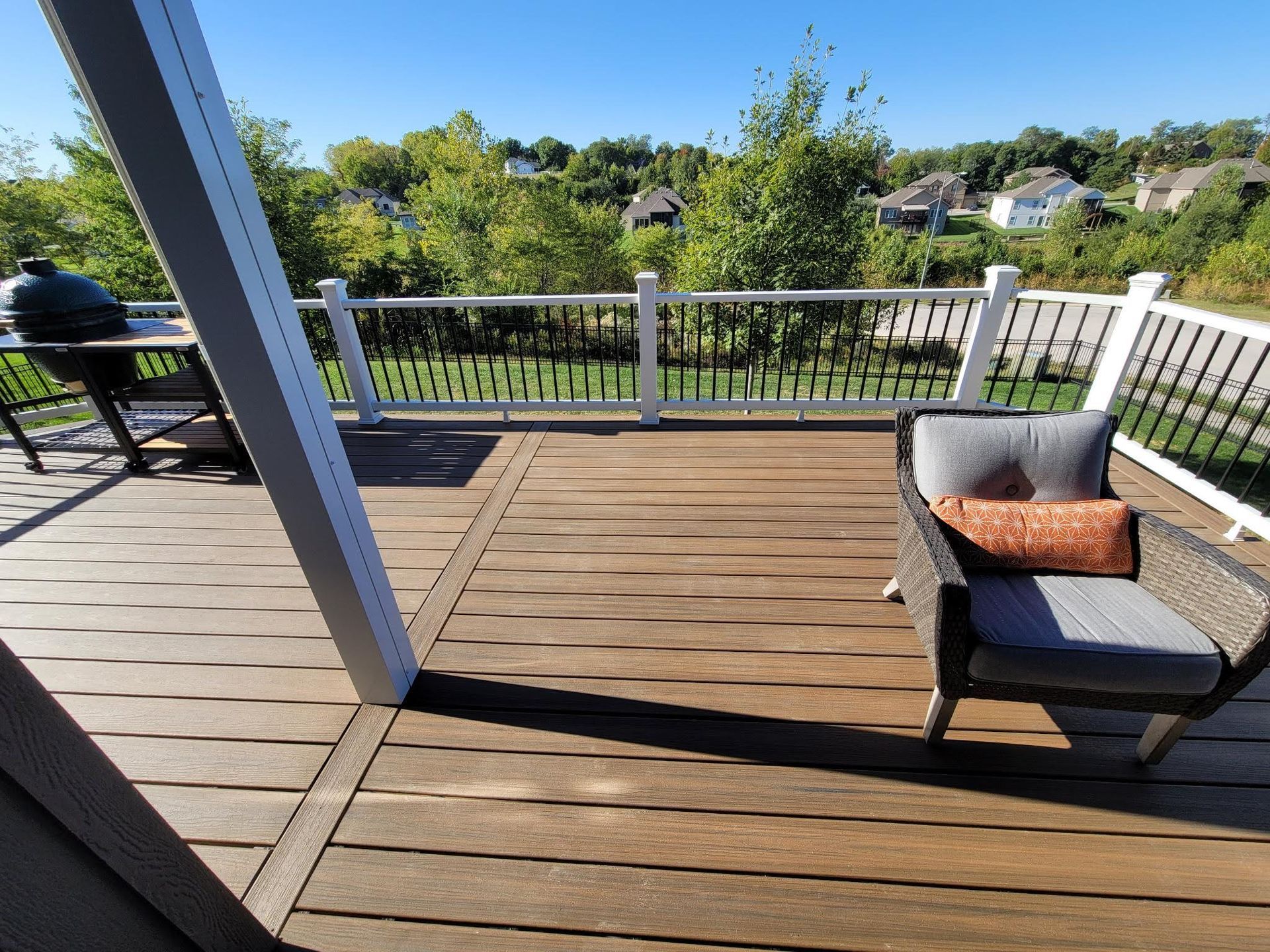 A wooden deck with a chair and a grill on it