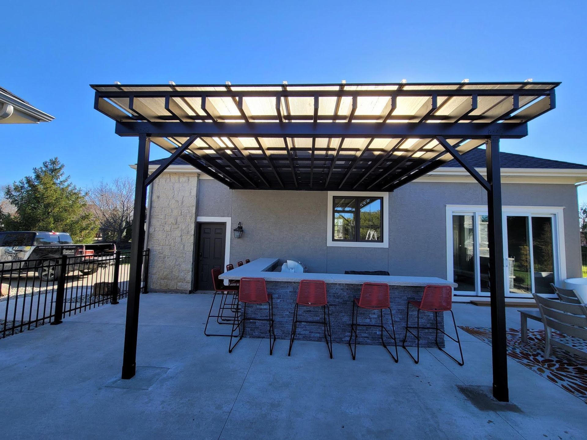 A patio with a pergola and stools underneath it