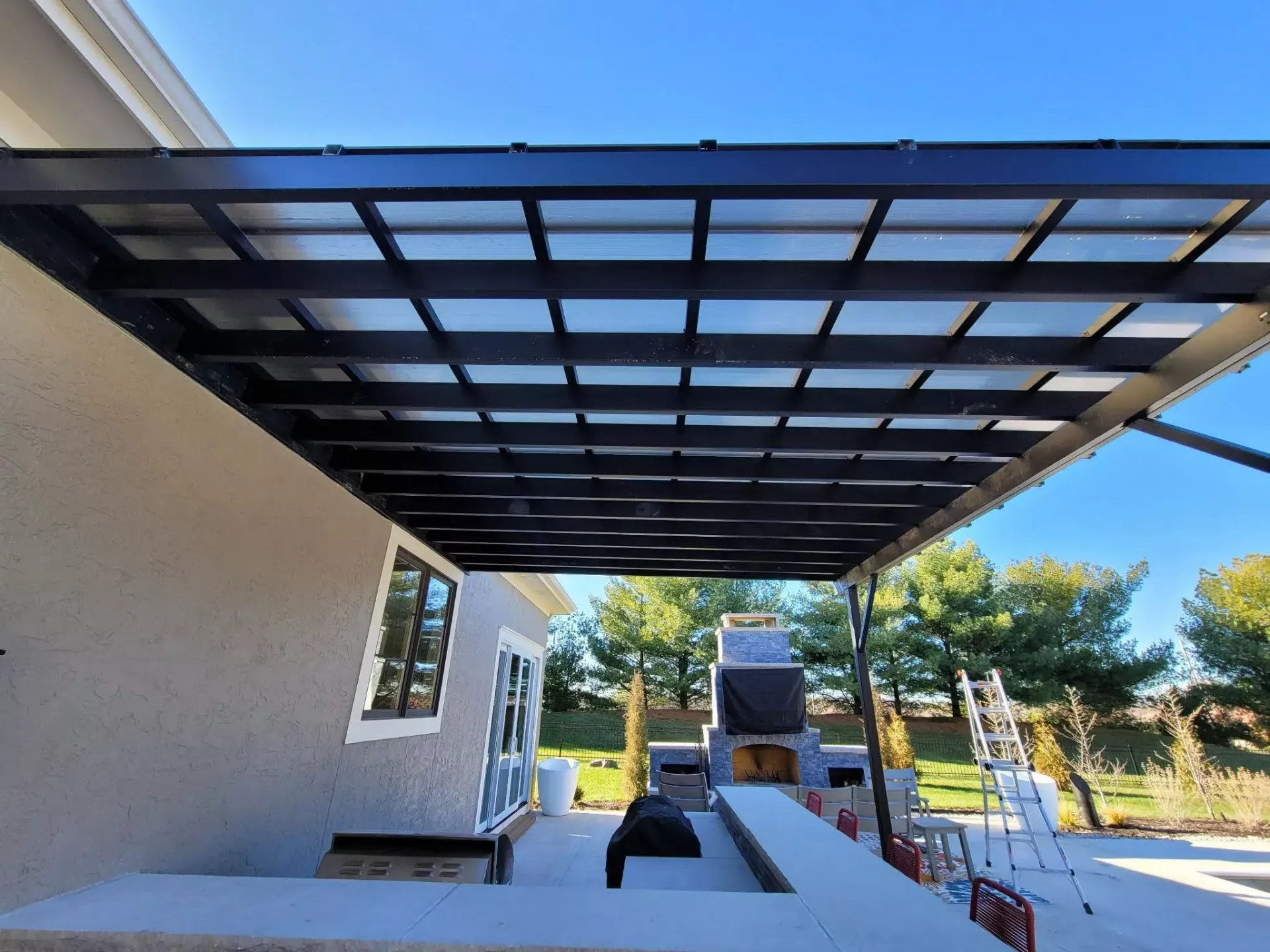 A patio with a covered area and a fireplace underneath it.