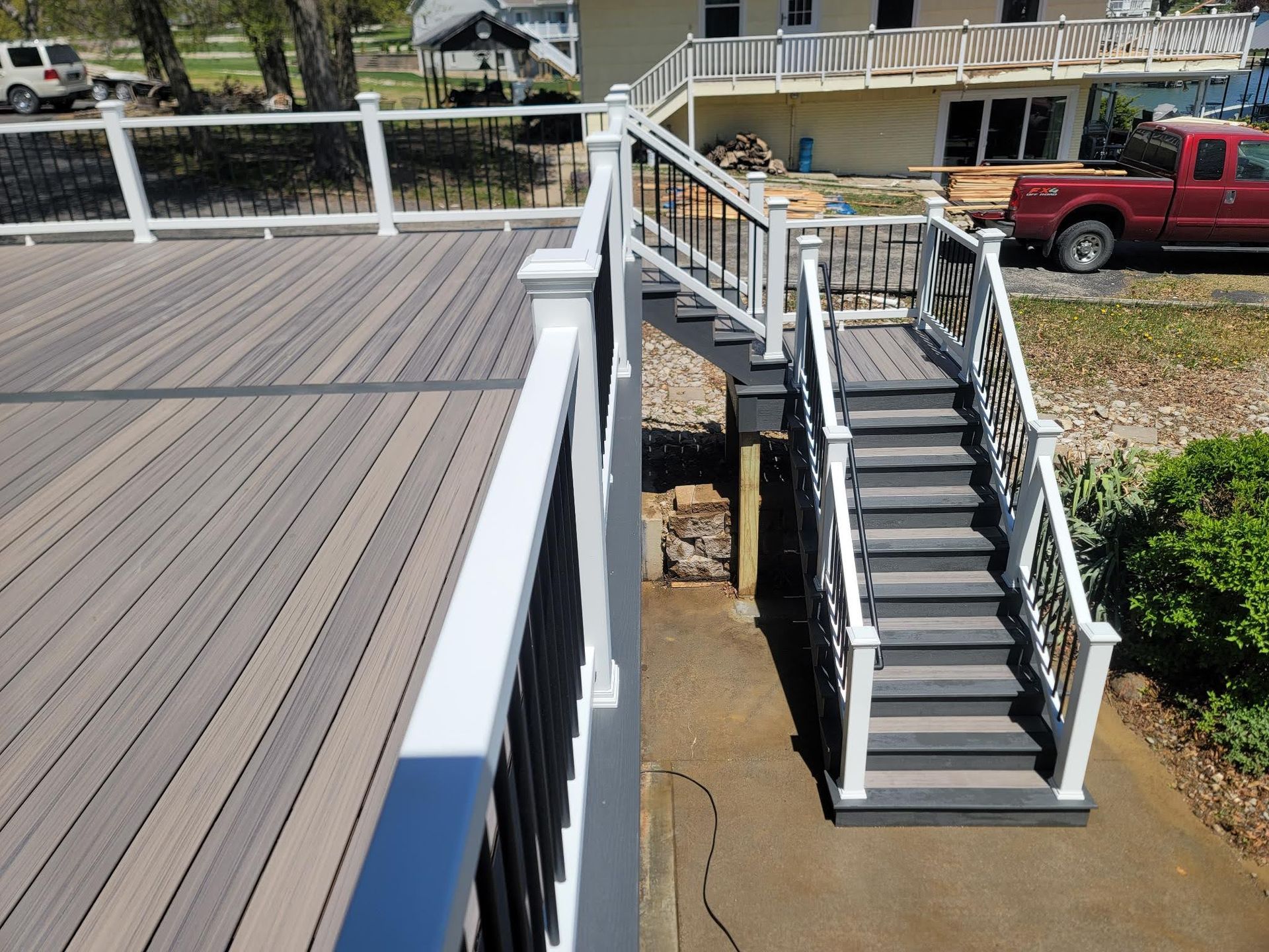 A red truck is parked in front of a deck with stairs leading up to it.