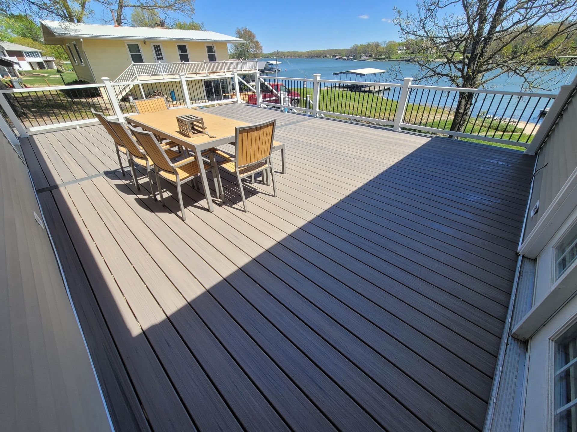 A large deck with a table and chairs overlooking a lake