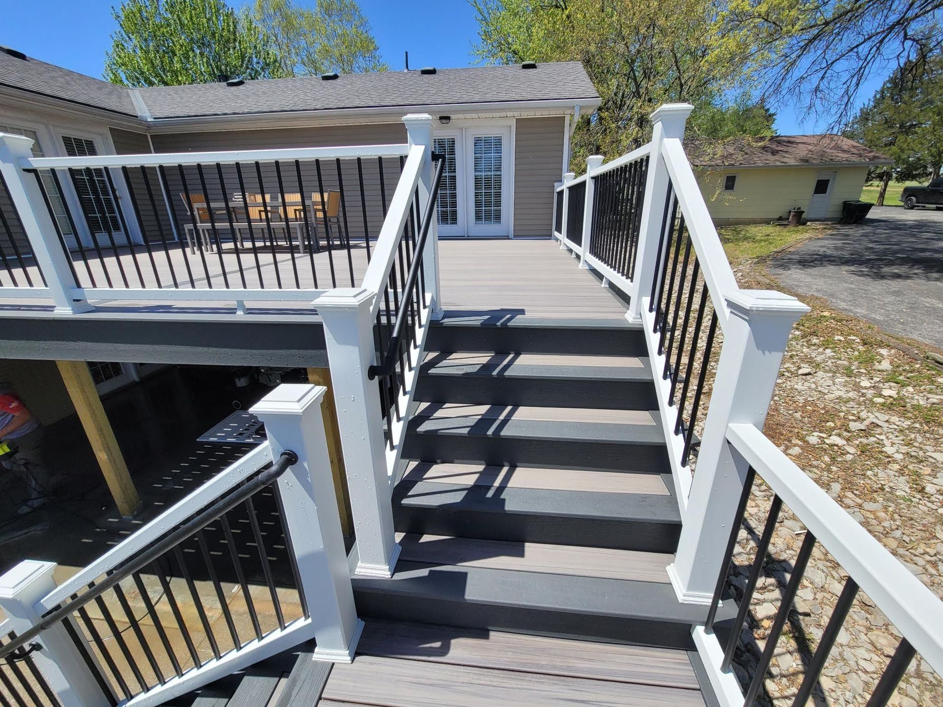 A deck with stairs leading up to it and a house in the background.