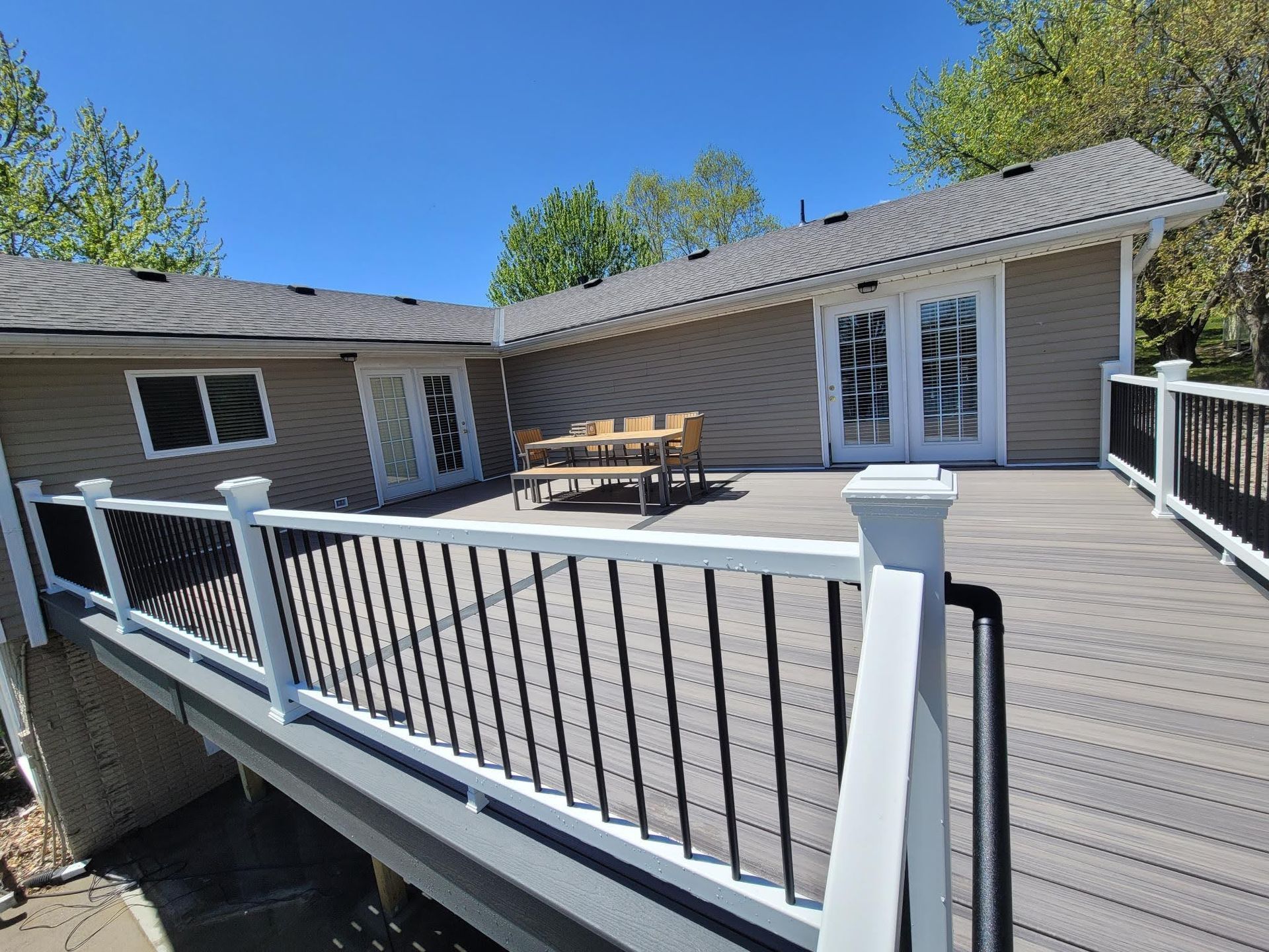 A large deck with a table and chairs on it in front of a house.