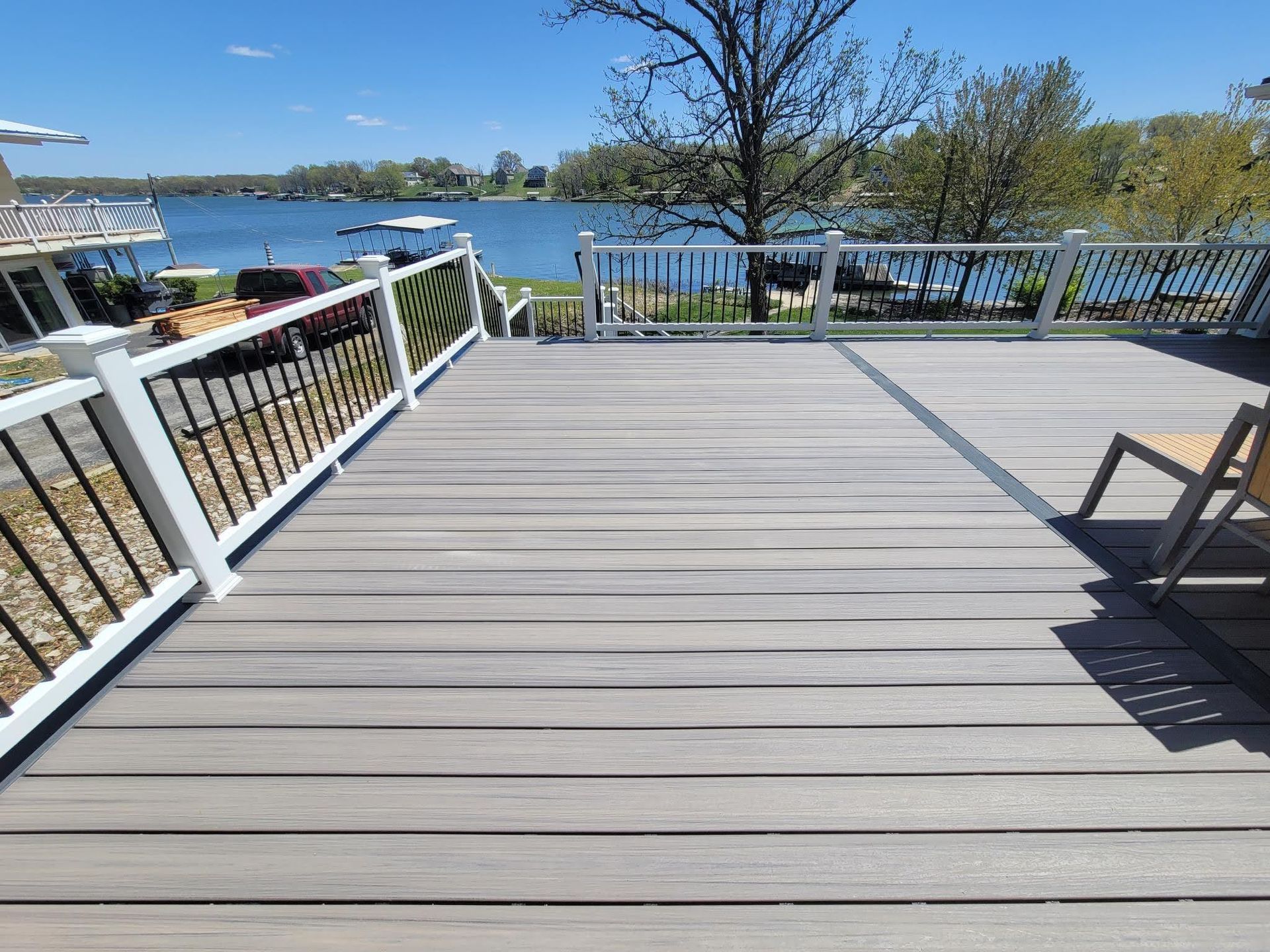 A wooden deck with a white railing overlooking a lake