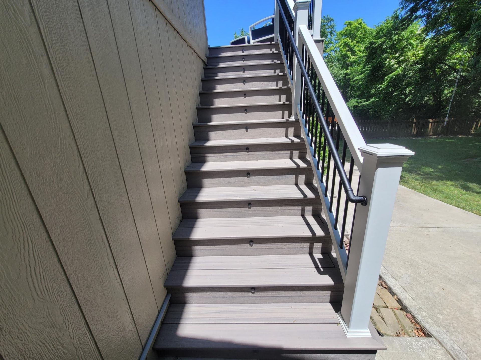 A set of stairs leading up to a deck with a white railing.