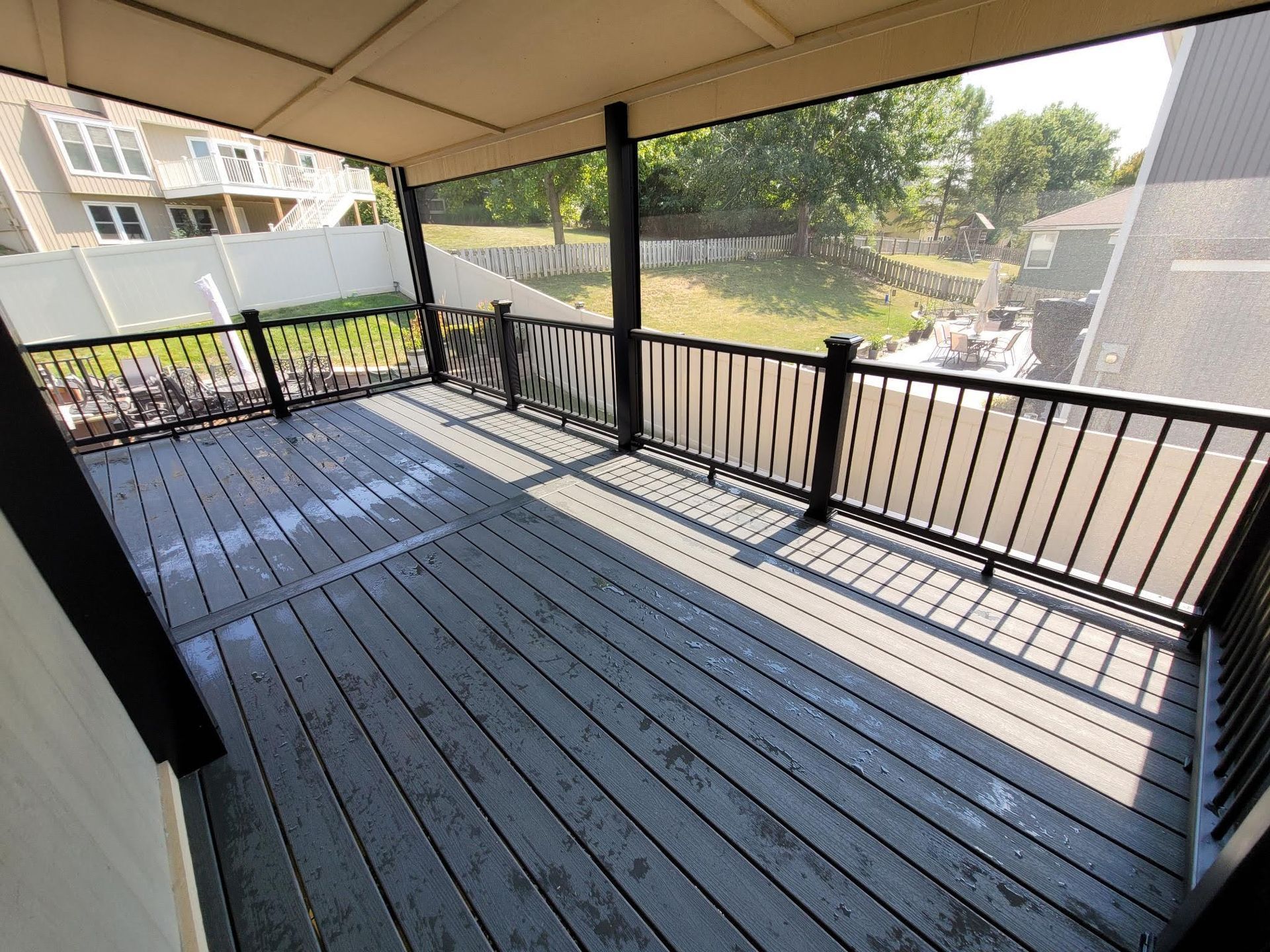 An empty deck with a screened in porch and a black railing