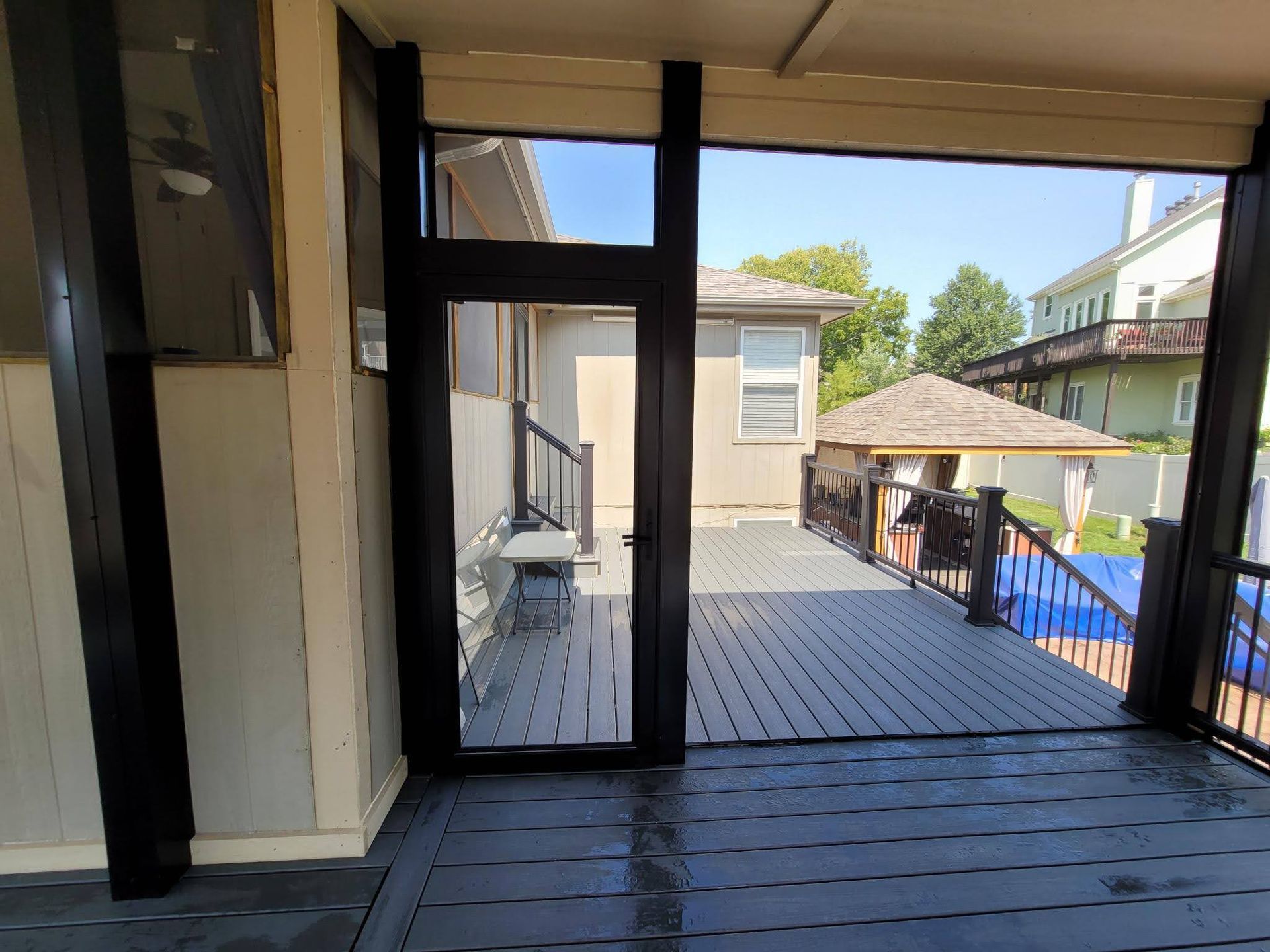 A screened in porch with a sliding glass door leading to a deck.