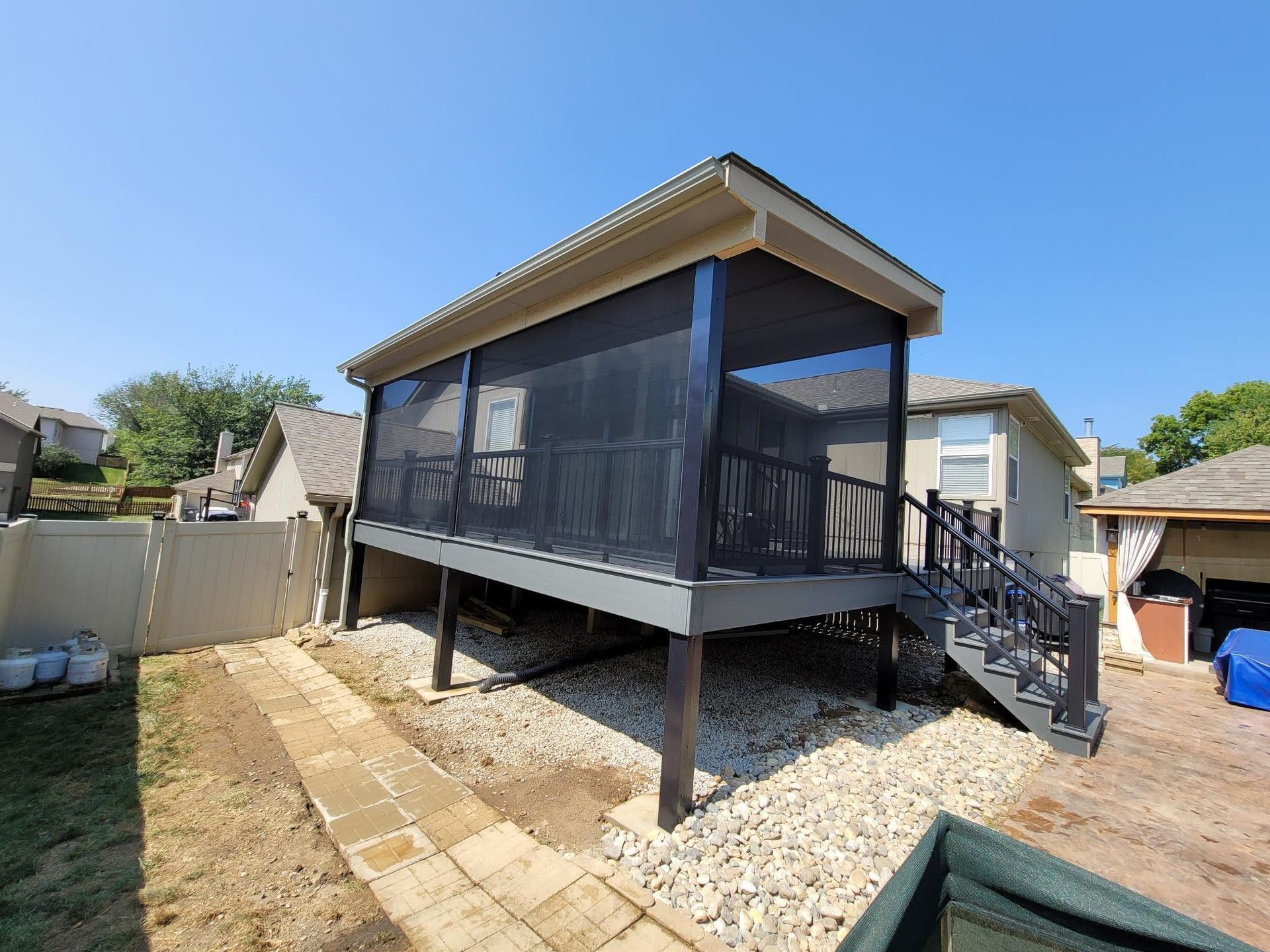 A screened in porch with stairs in the backyard of a house.