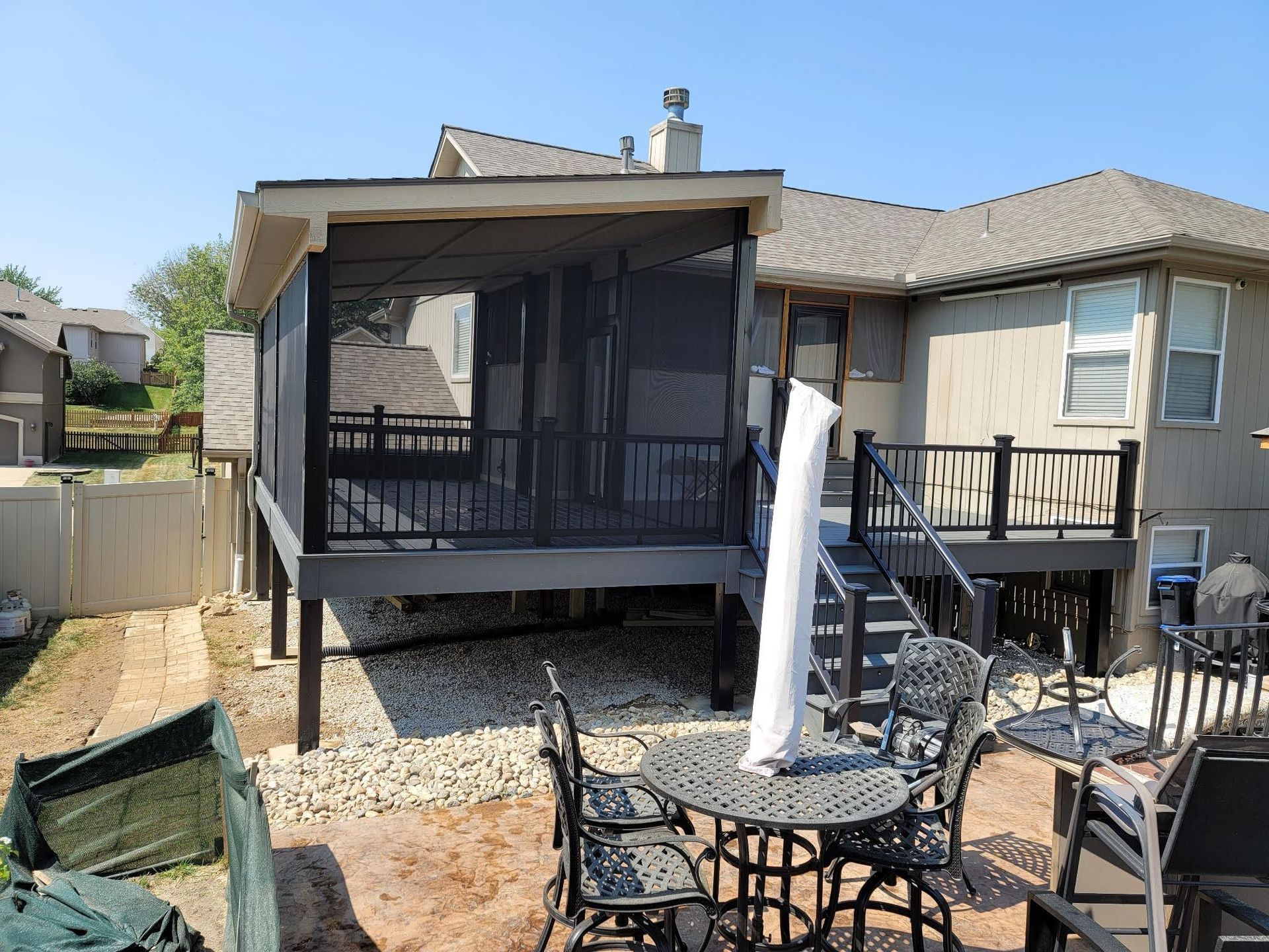 A screened in porch with a table and chairs in front of a house.