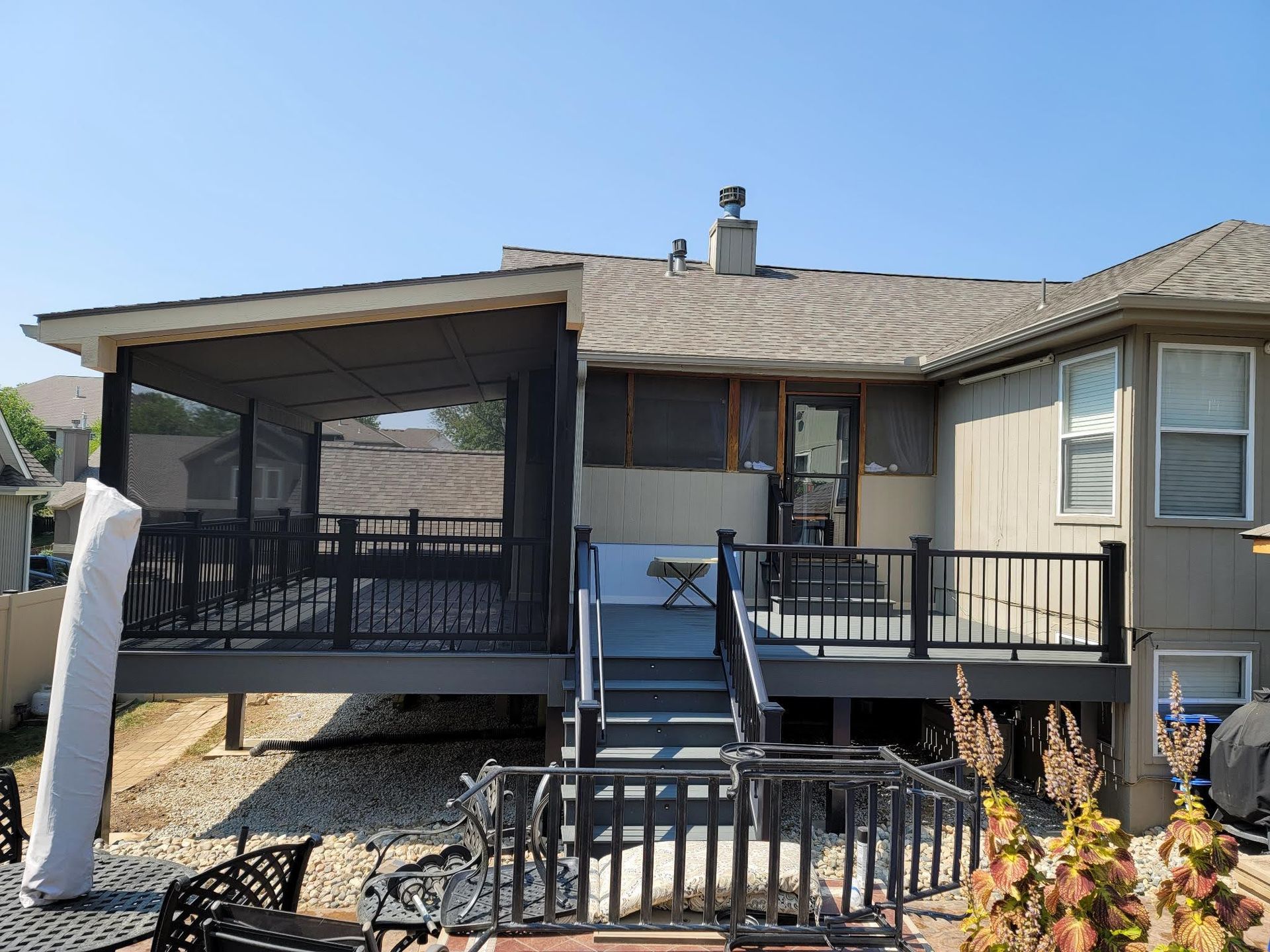 The back of a house with a screened in porch and stairs leading up to it.