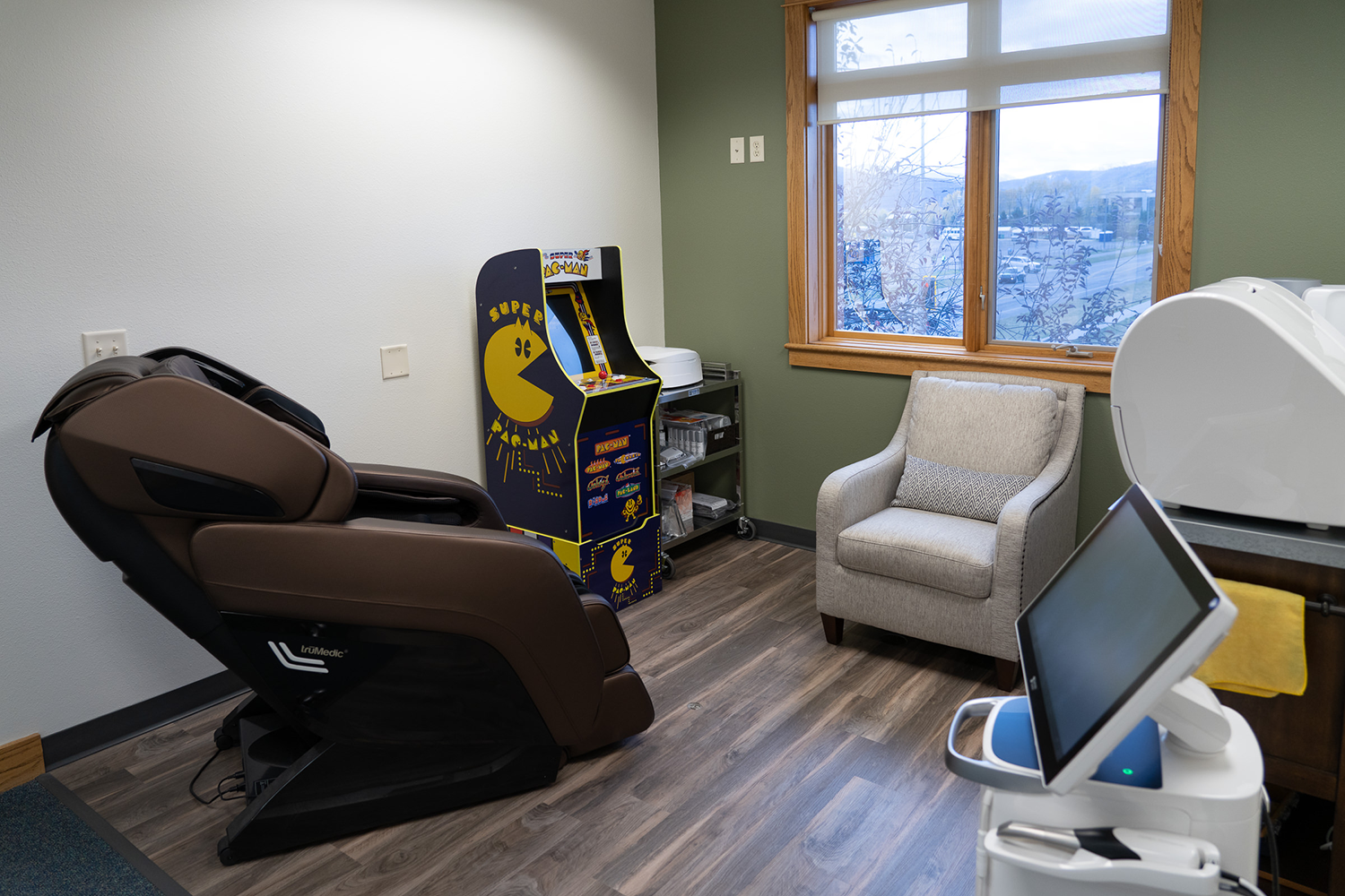 A room with a massage chair , chair , and arcade machine.
