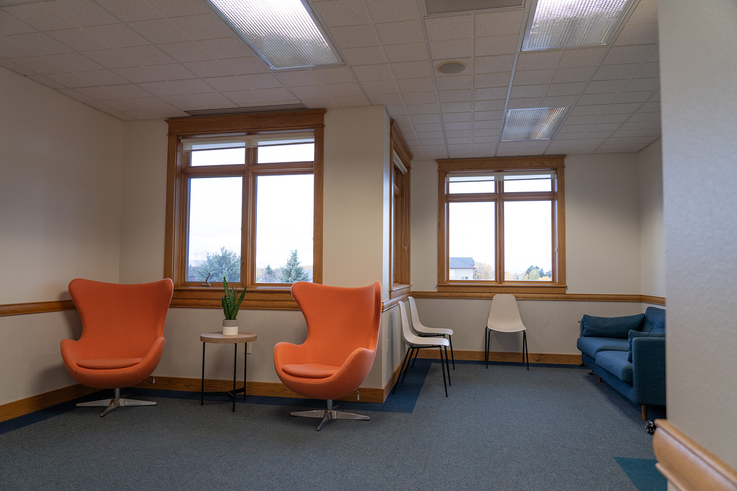 A waiting room with orange chairs and a blue couch