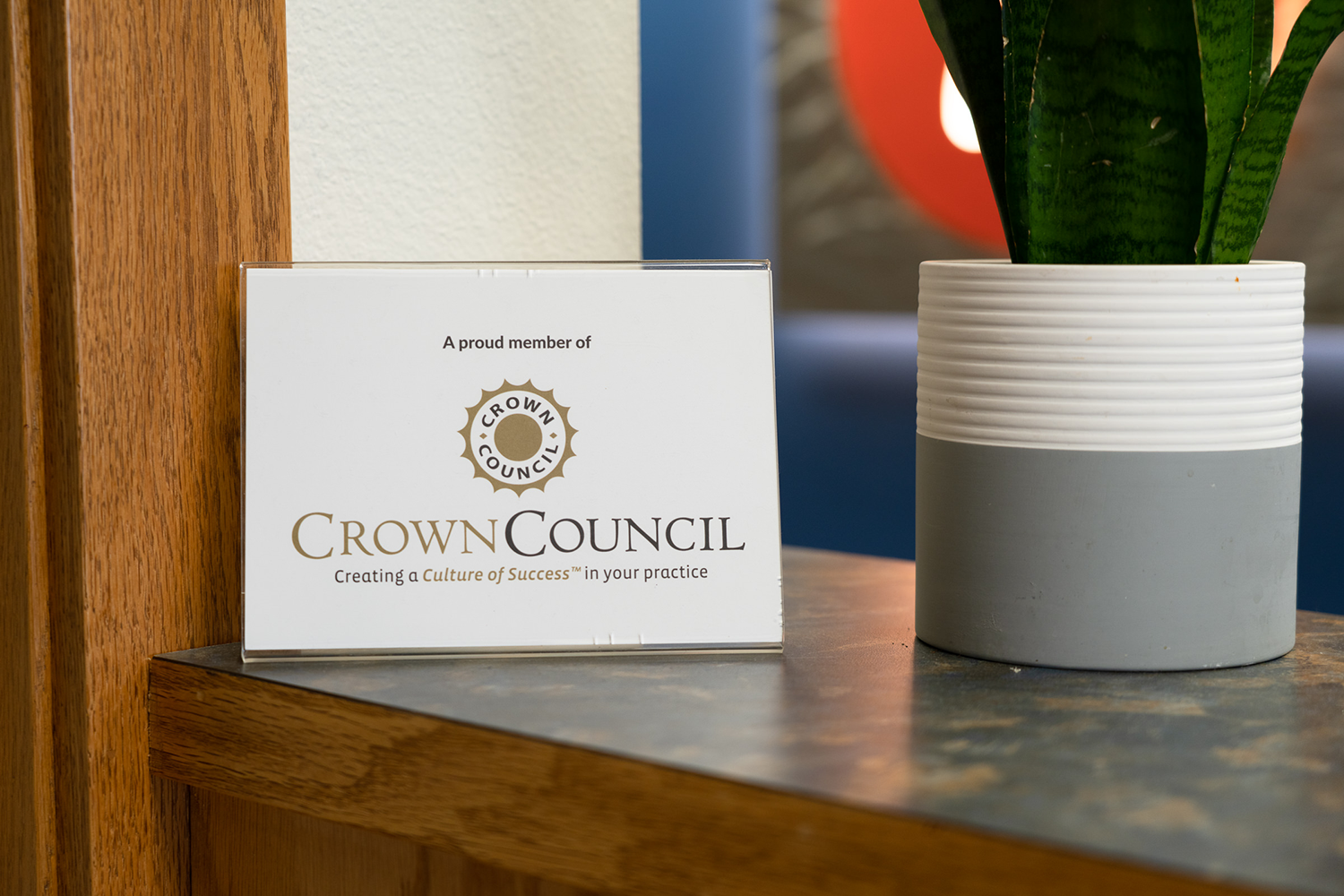 A crown council sign is sitting on a table next to a potted plant.