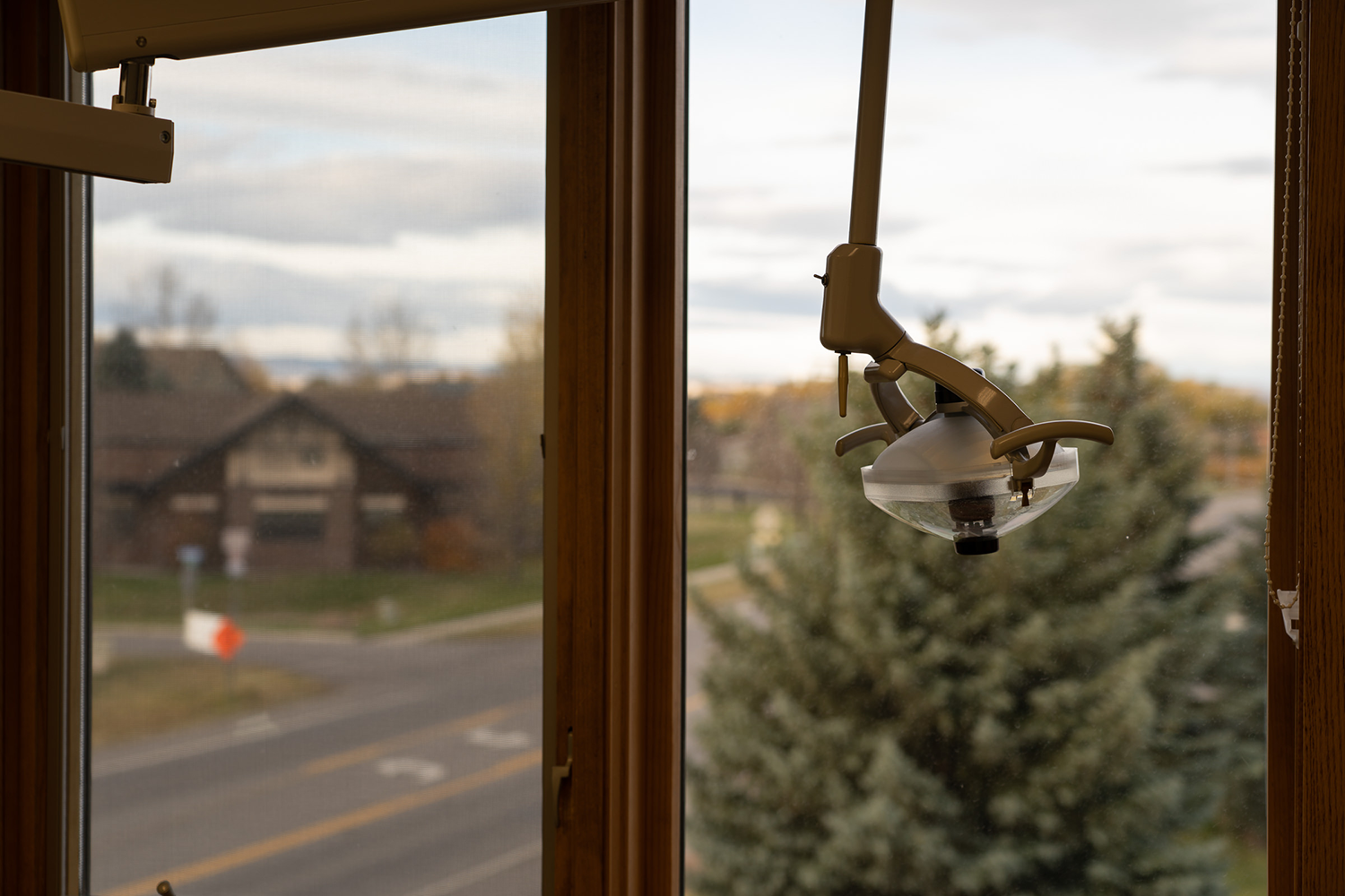 A dental light is hanging from the ceiling in front of a window.