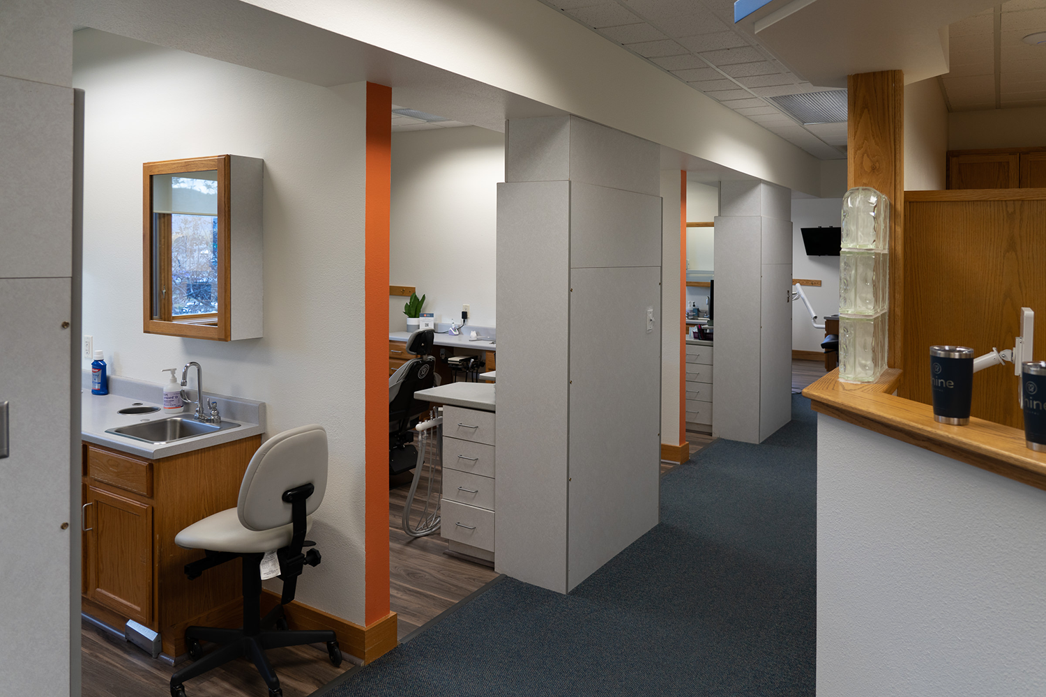 A dental office with a chair and a sink.