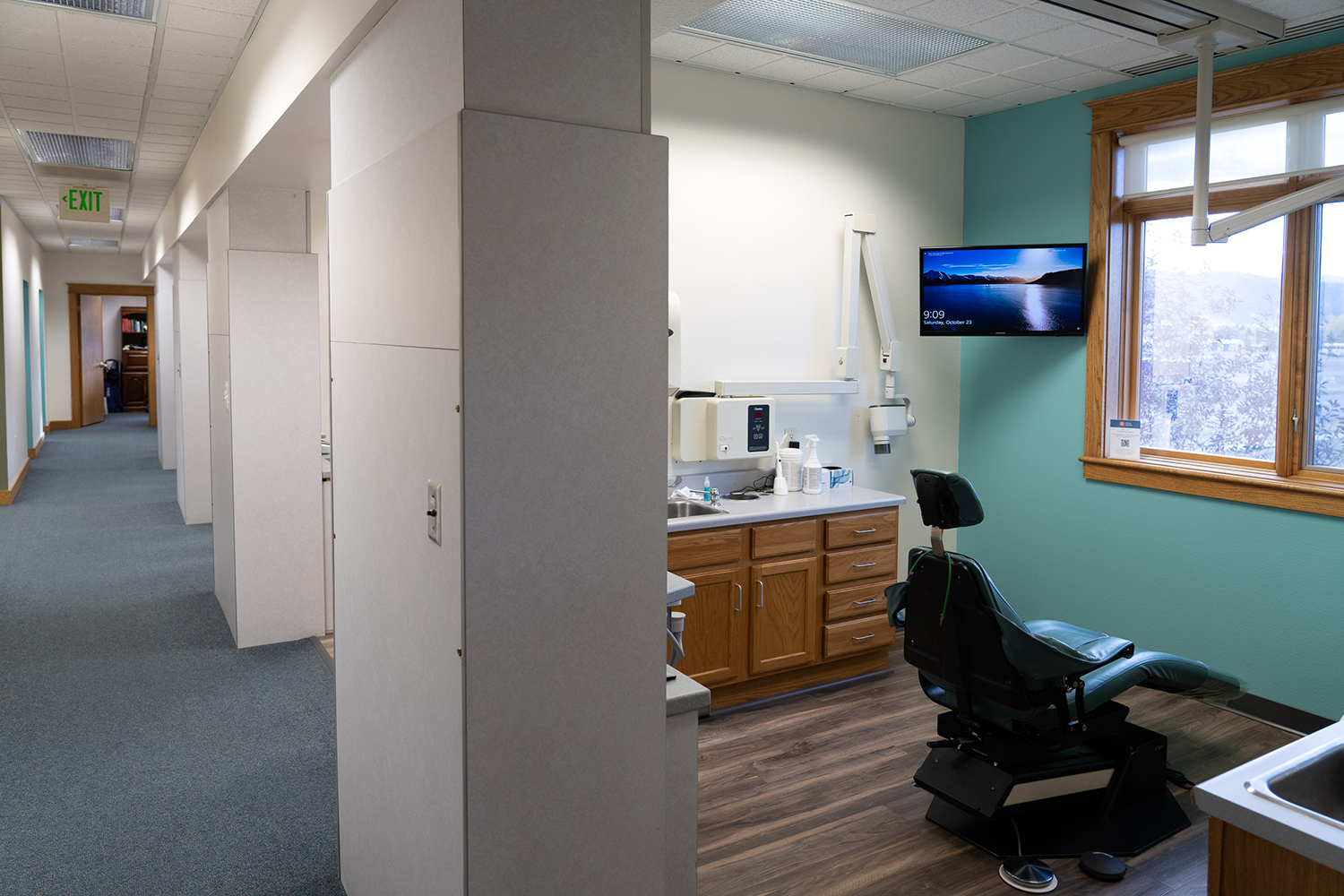 A dental office with a dental chair and a television on the wall.