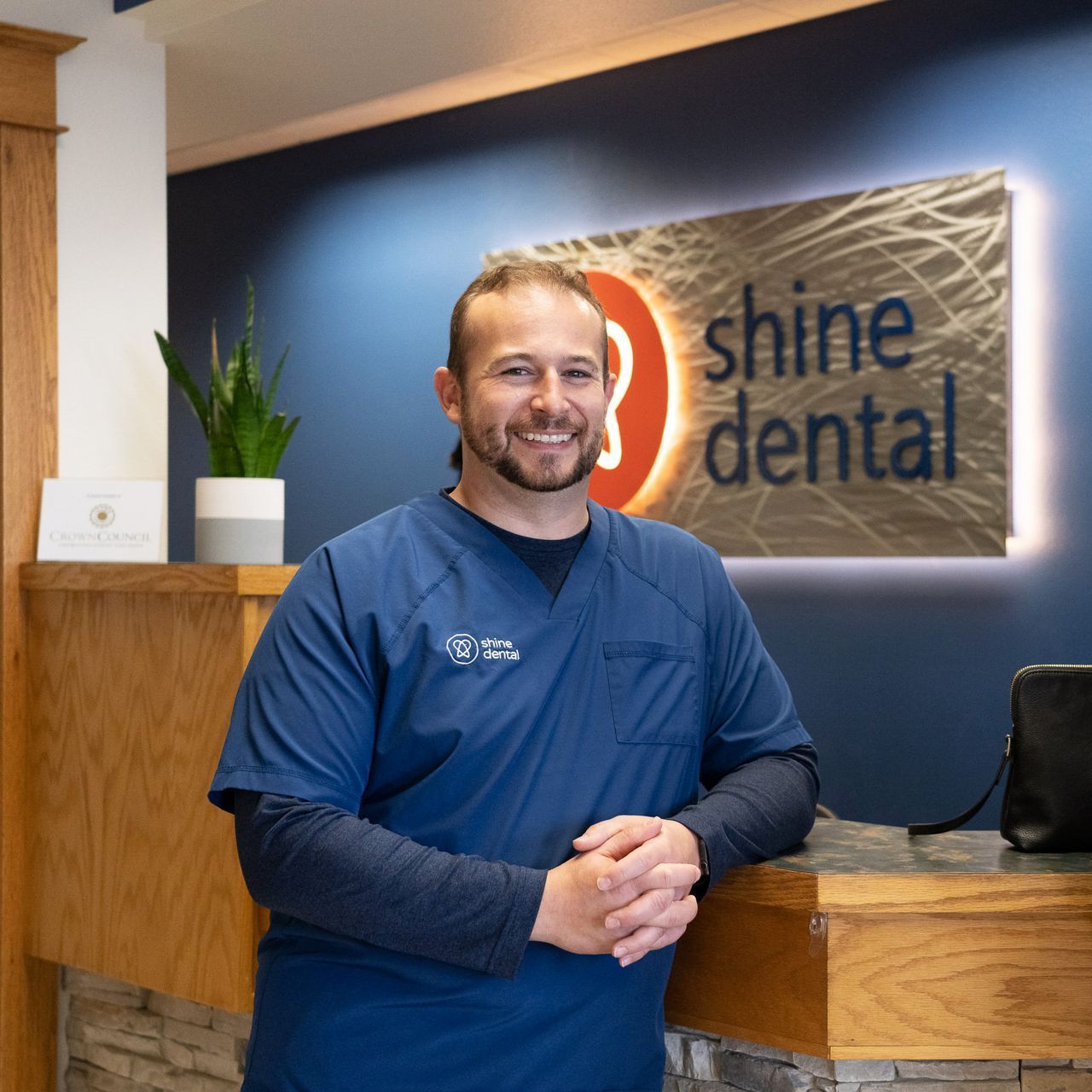 Dr. Justensen standing in front of reception desk smiling with logo in the background