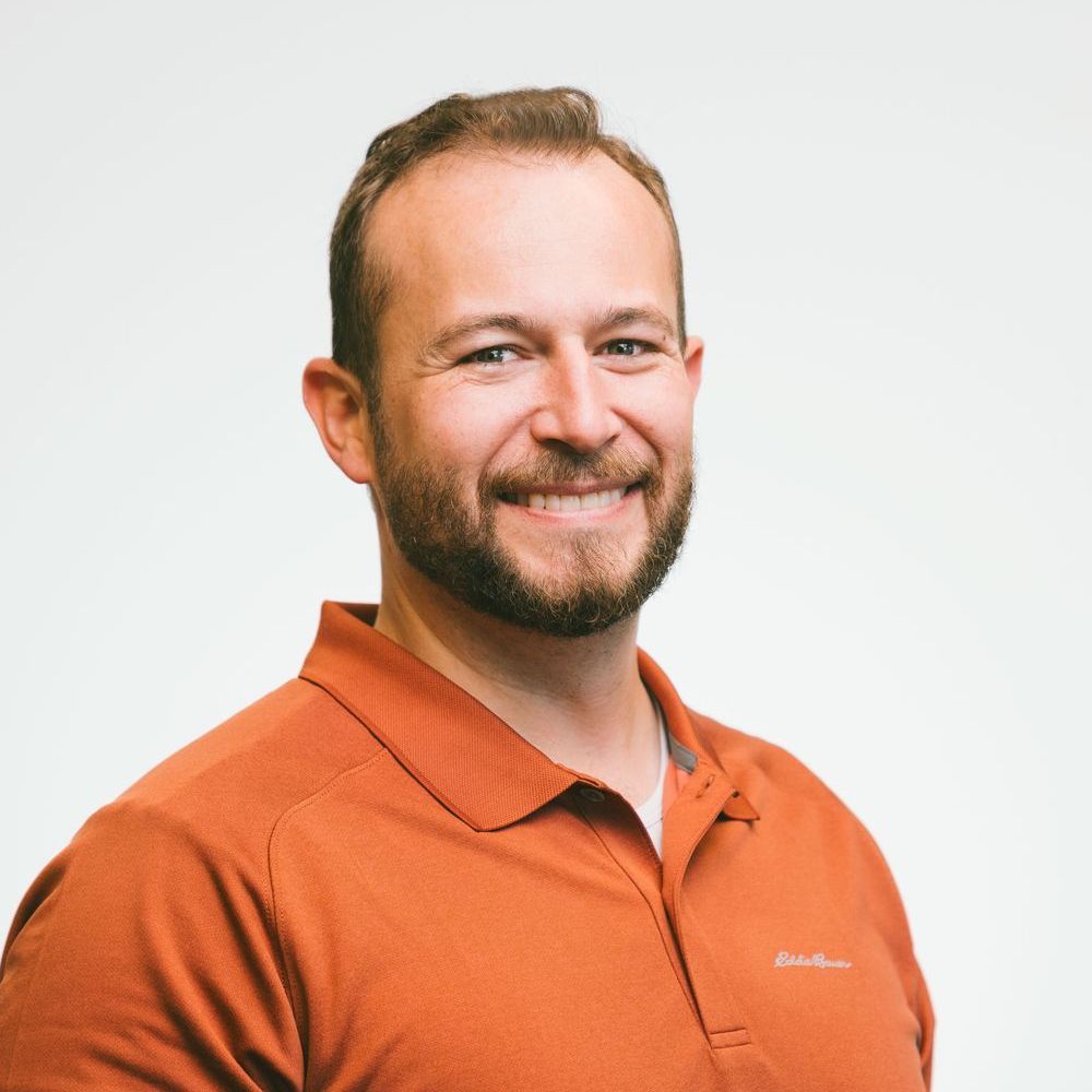A man in a blue scrub is standing in front of a shine dental sign.