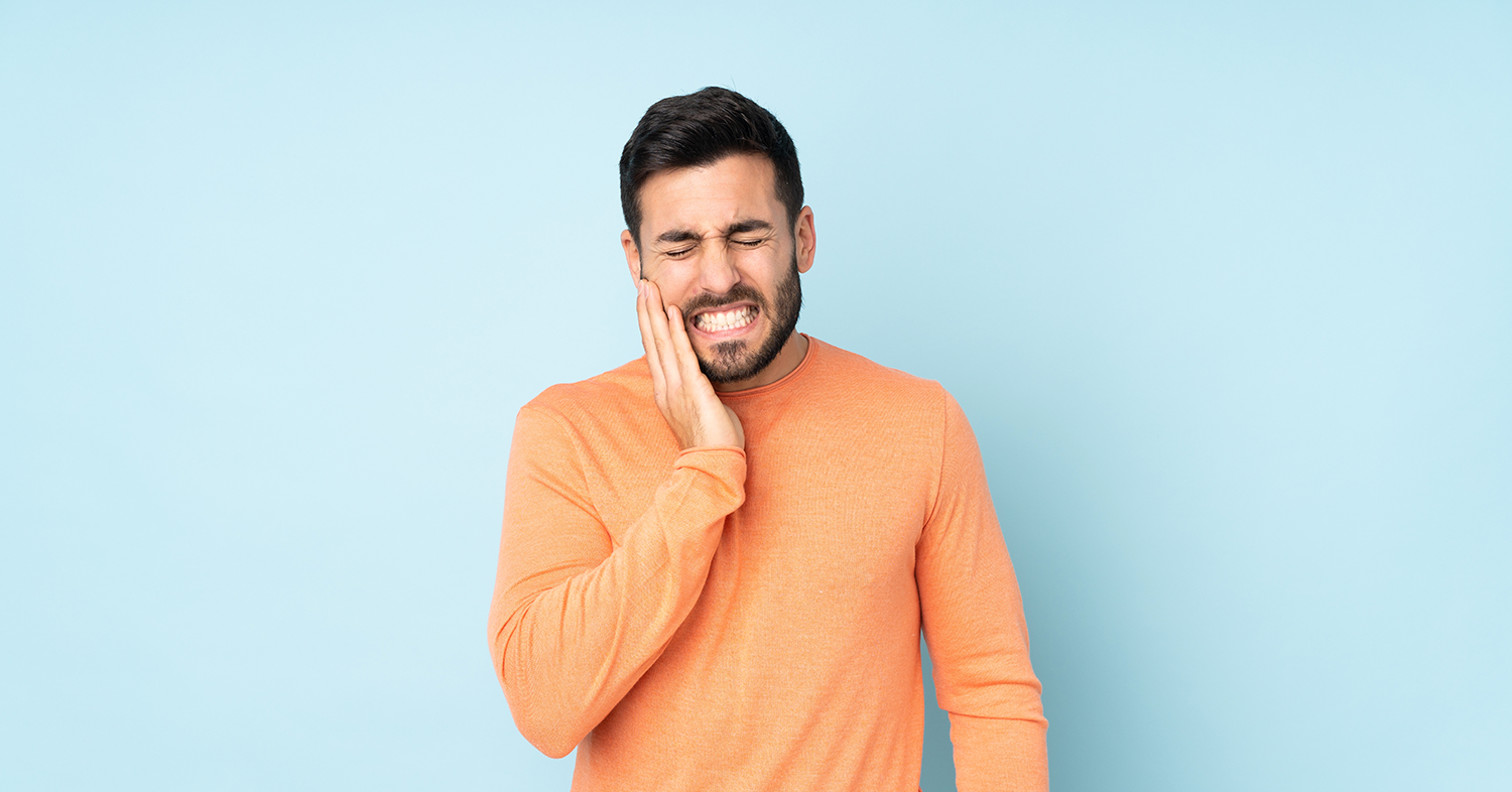 A man is holding his face in pain because of a toothache.