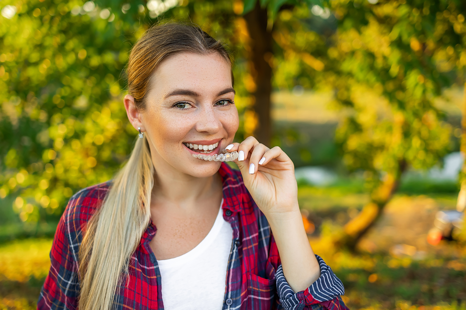 A woman is eating a candy bar in a park.