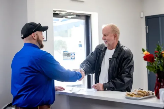 Employee shaking hands with customer at front desk | Bavarian Motor Cars