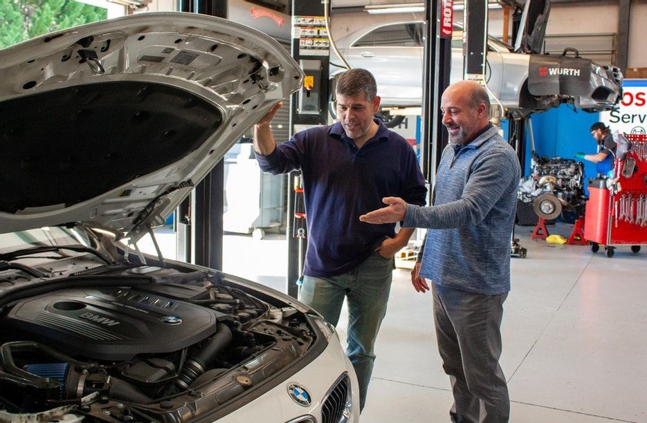 Two employees looking at engine of car with hood open | Bavarian Motor Cars