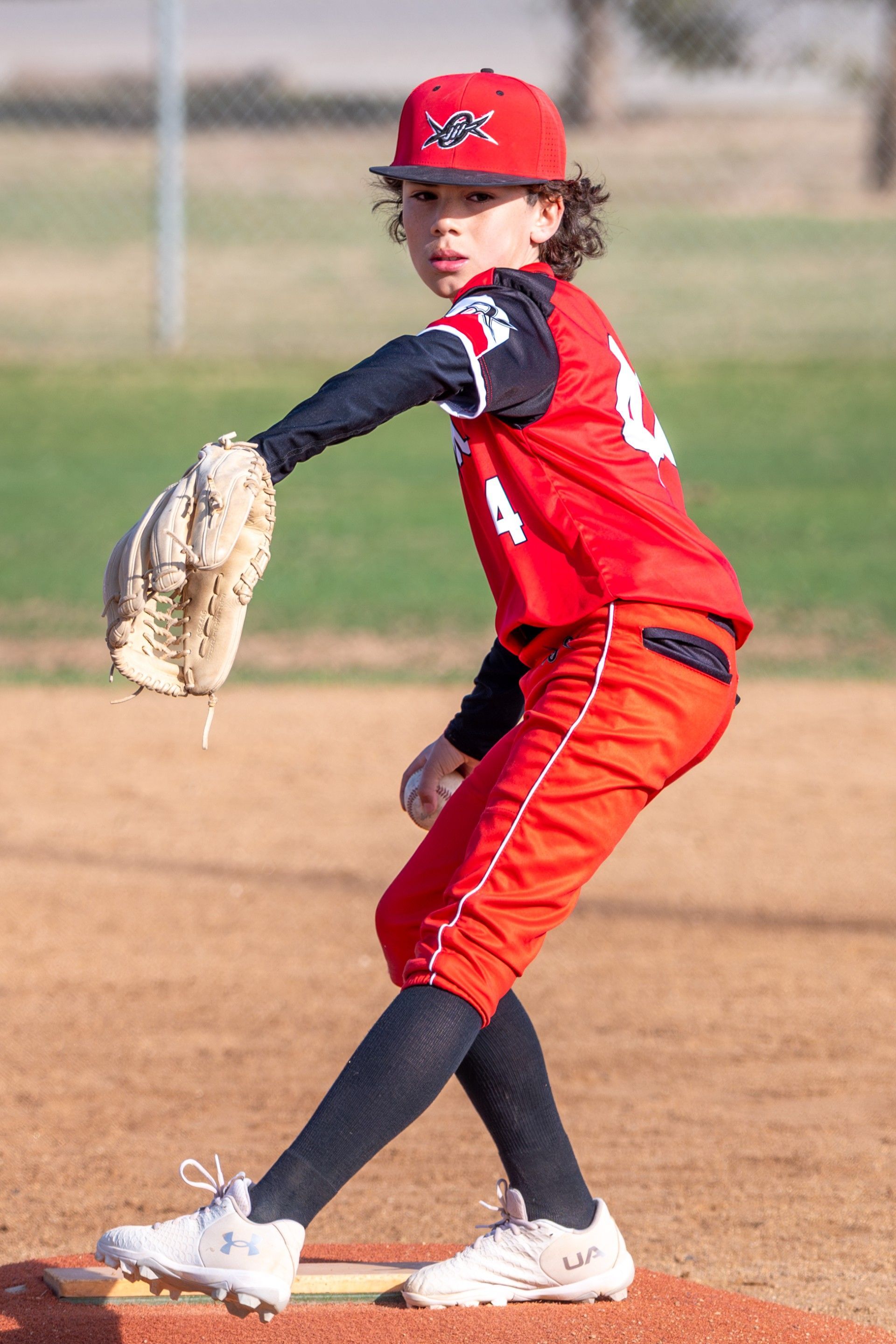 A young boy is swinging a baseball bat on a baseball field.