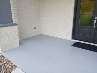 Grey painted porch with brick wall and black front door.