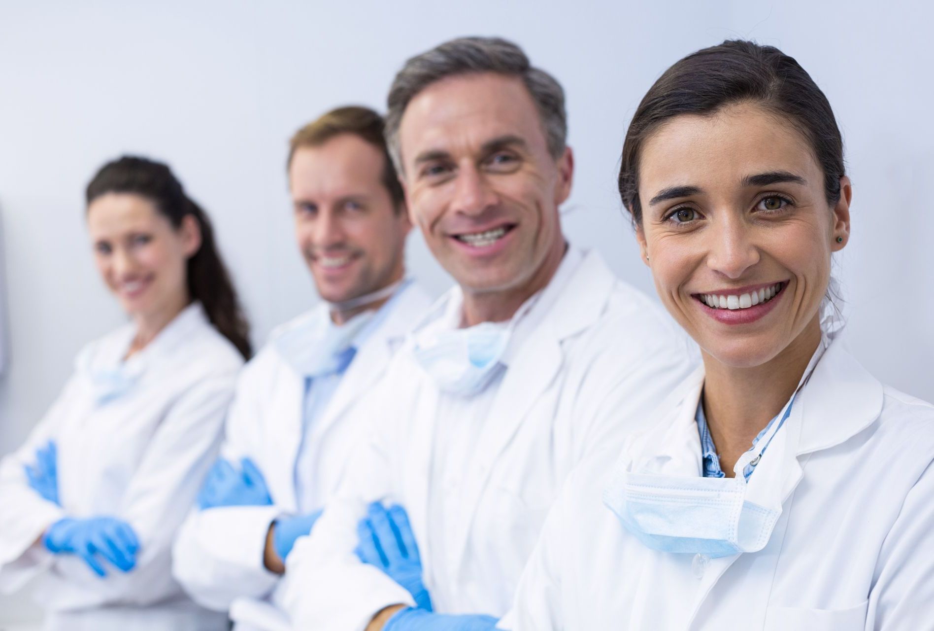 A group of dentists are standing in a row with their arms crossed and smiling