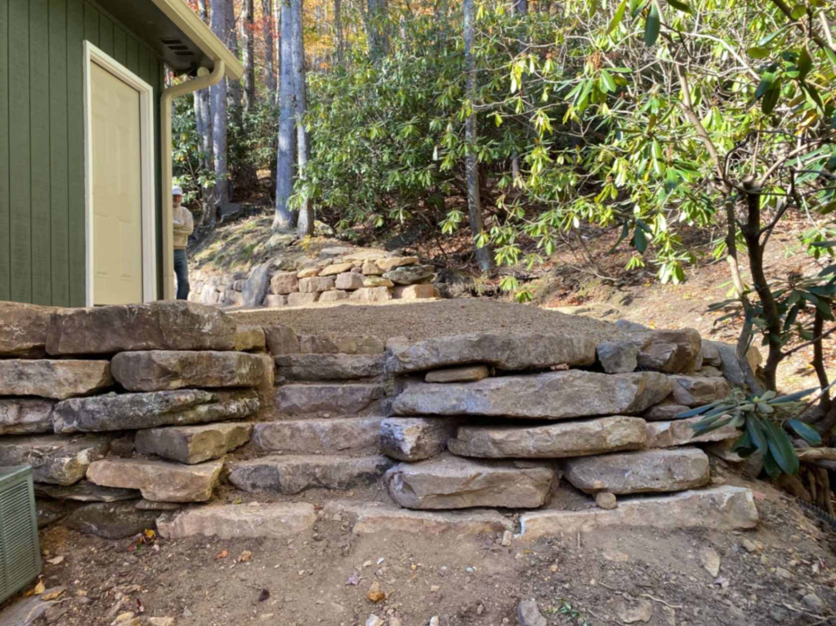 Stone steps leading up a hillside, near a building and trees.