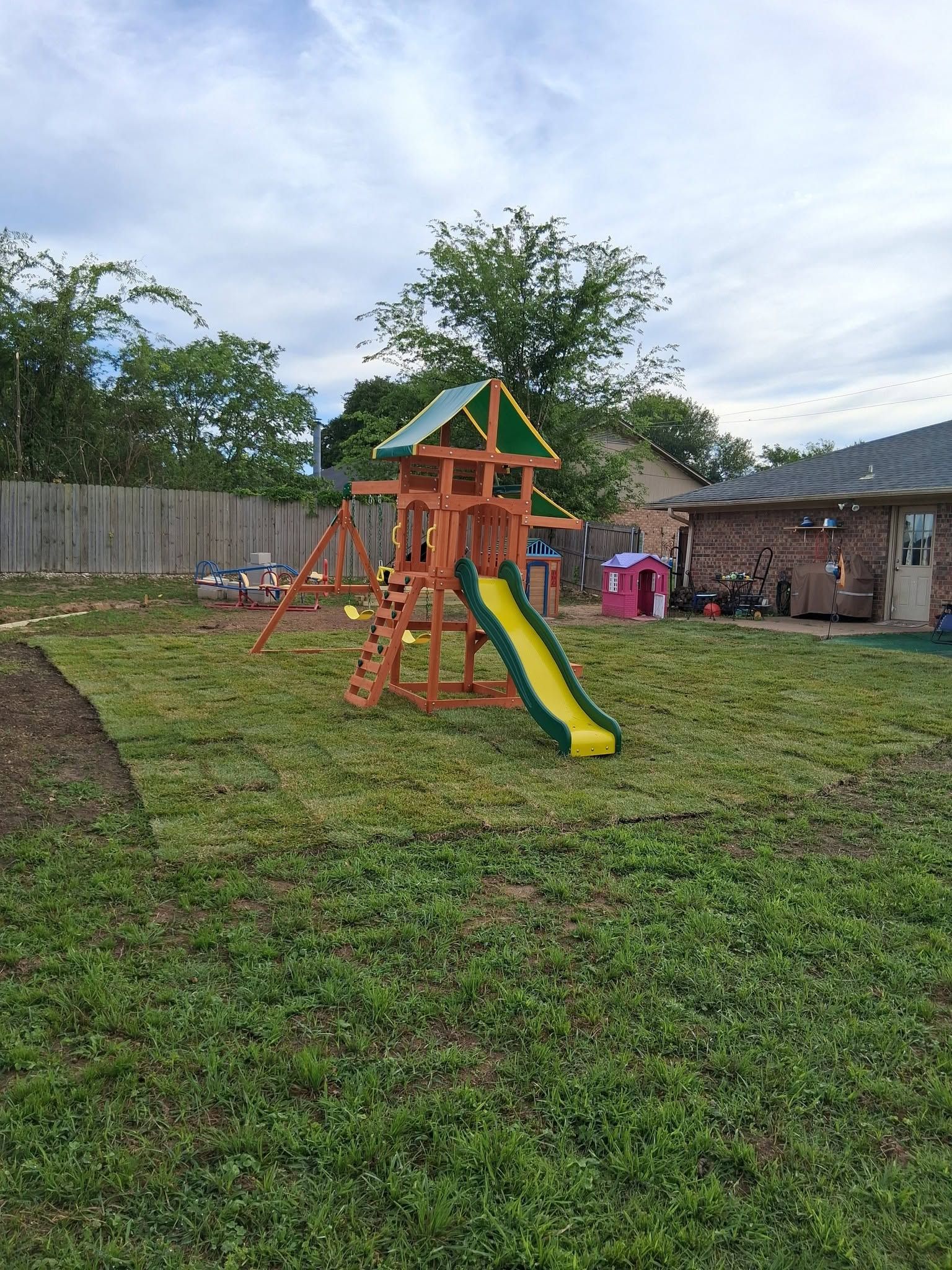 Children’s playground with orange playset, green slide, and small pavilion in a grassy yard
