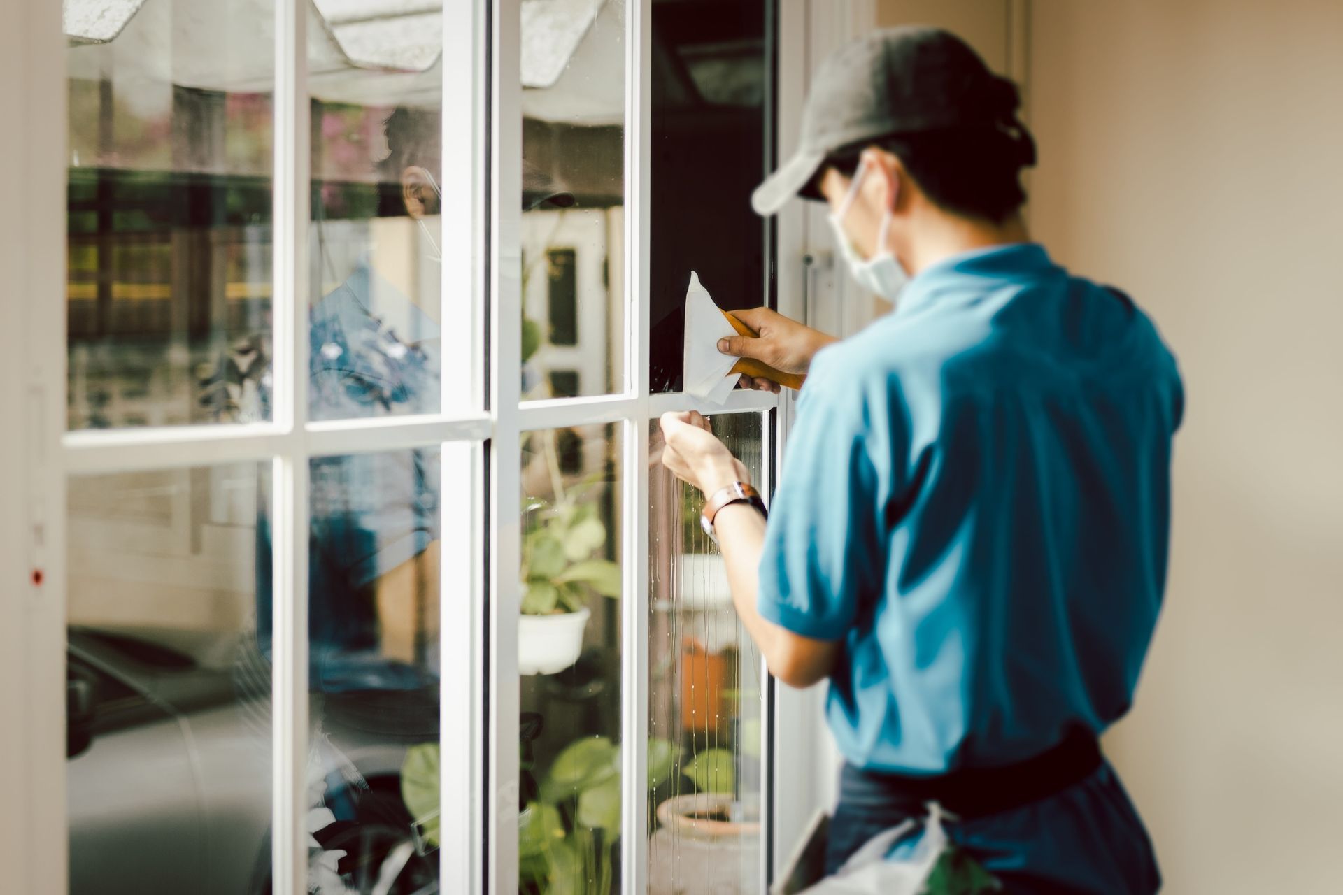 A man wearing a mask is cleaning a window.