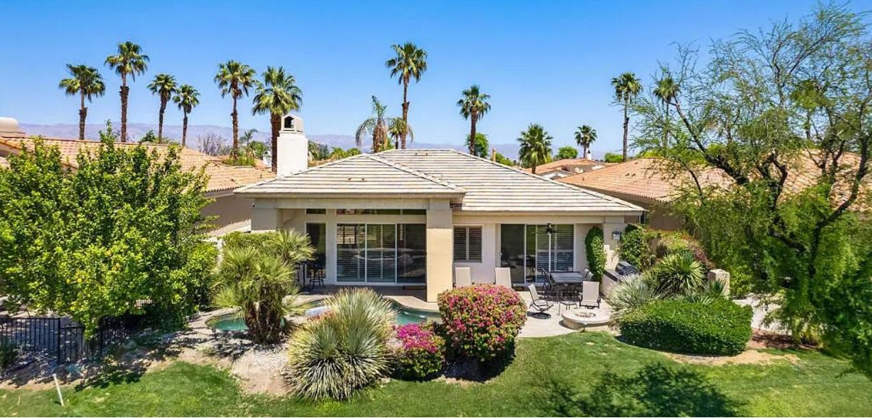An aerial view of a house with palm trees in the background.