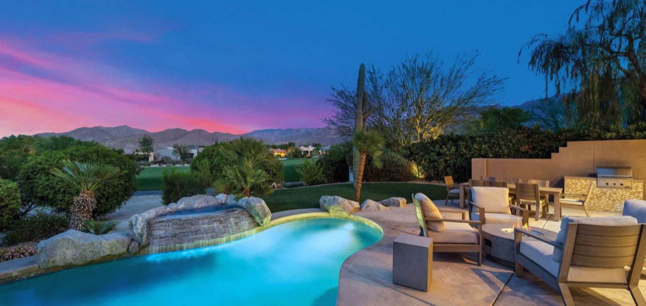 There is a large swimming pool in the backyard of a house.