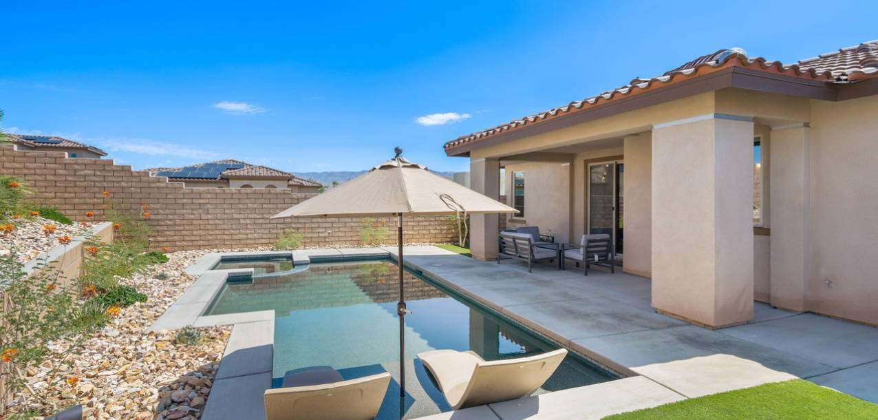 There is a large swimming pool in the backyard of a house.