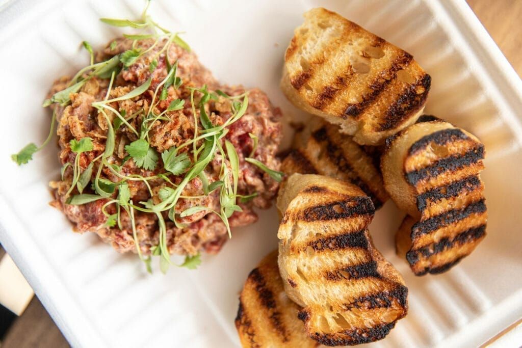 A plate of food with grilled bread and meat on a table.