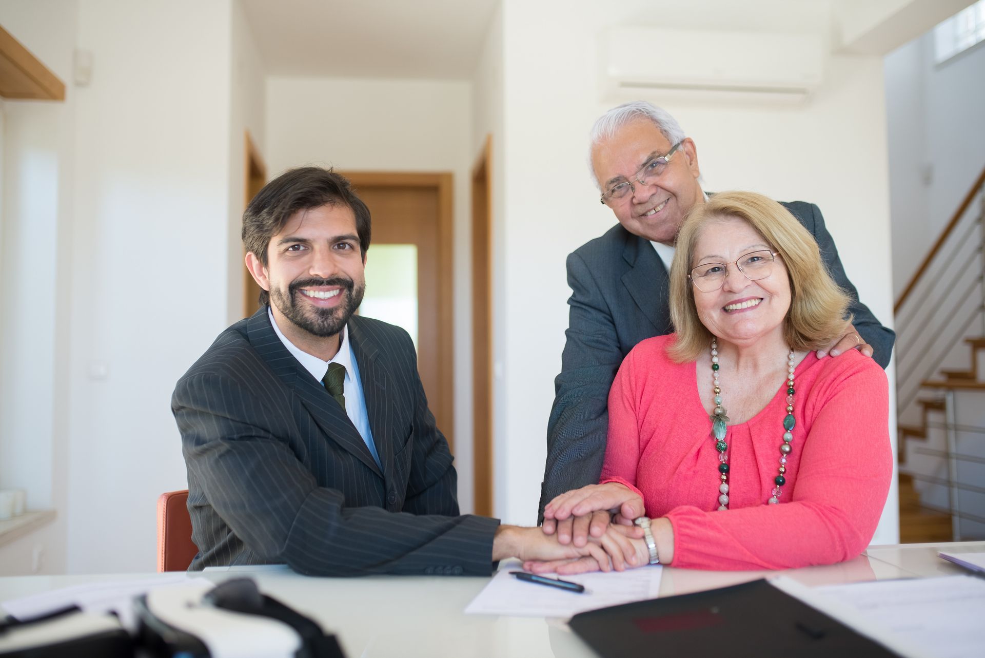 A man and a woman are sitting at a table with a man standing behind them.