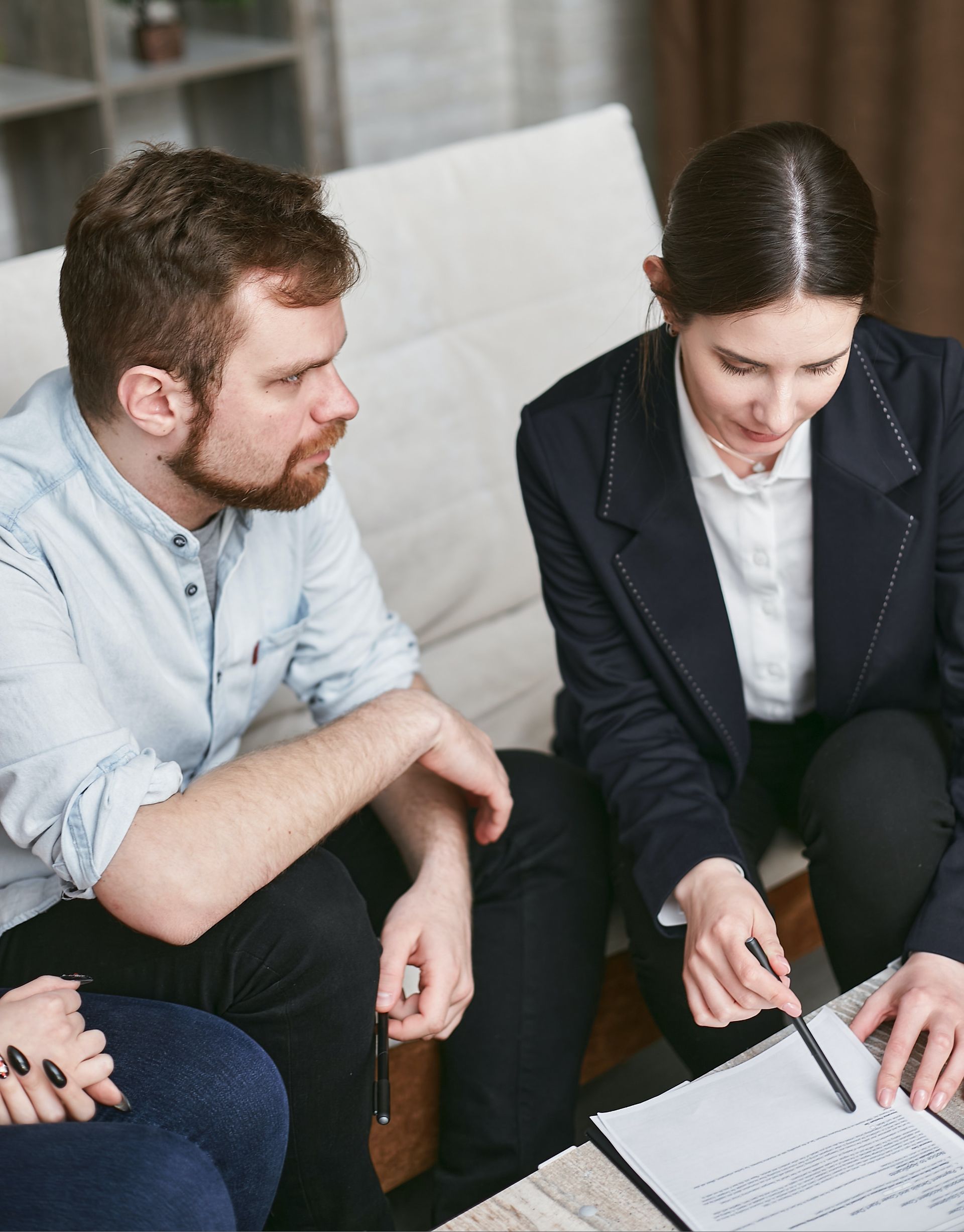 A group of people are sitting on a couch looking at a notebook.