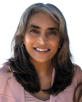 A woman in a pink jacket is smiling for the camera