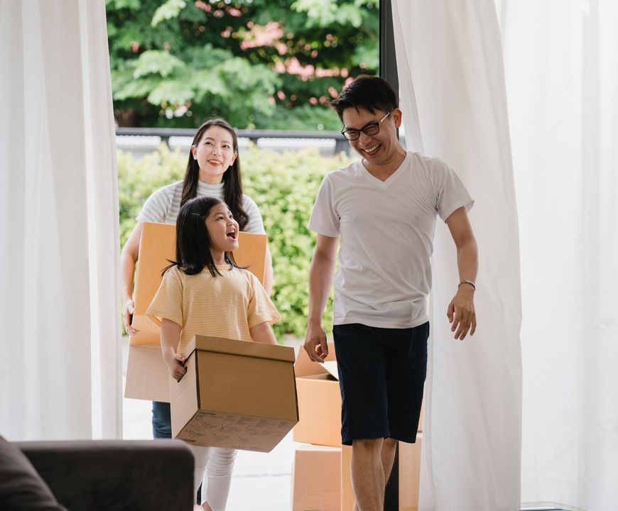 A family is moving into a new home and carrying boxes.