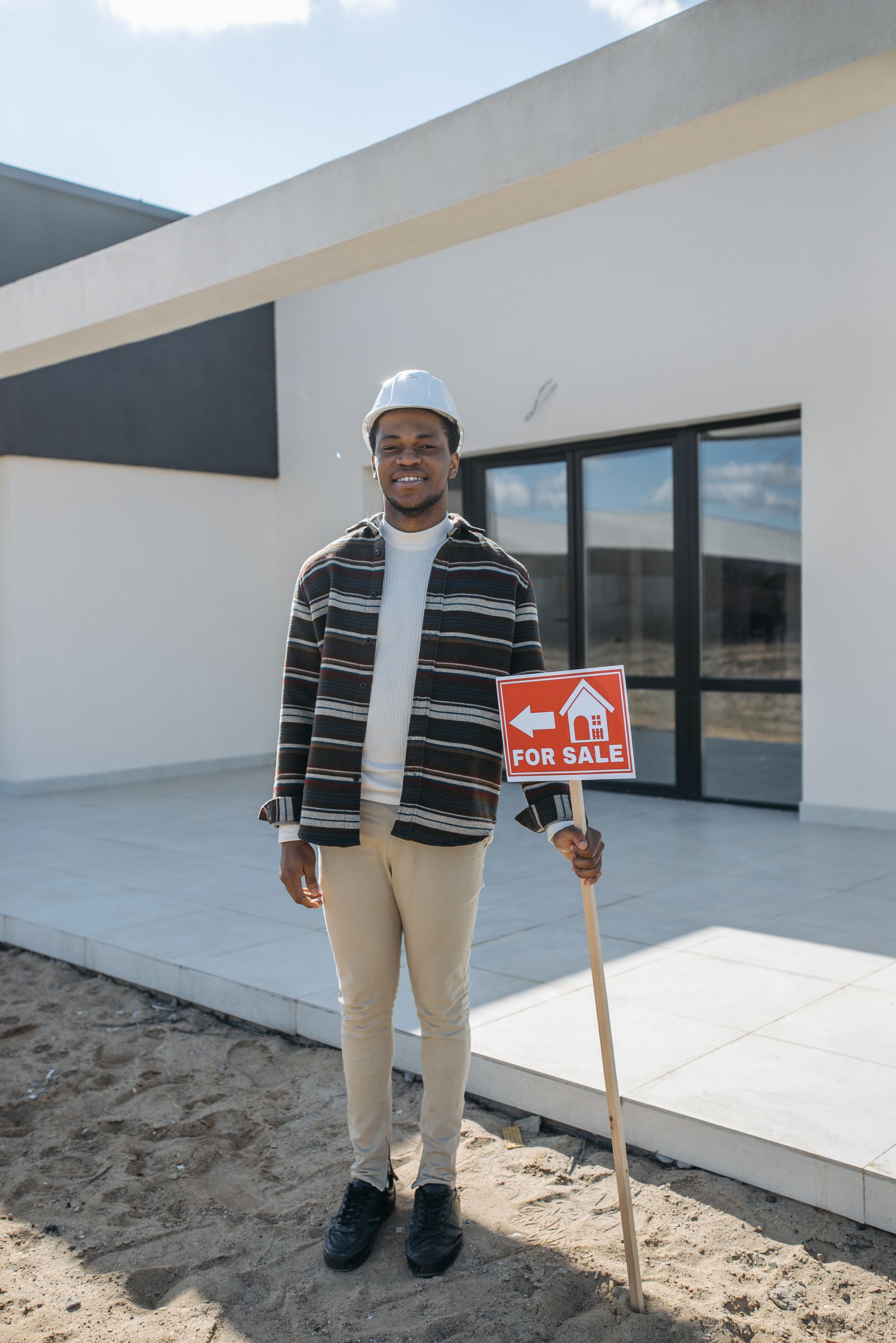 A man is standing in front of a house holding a sign.