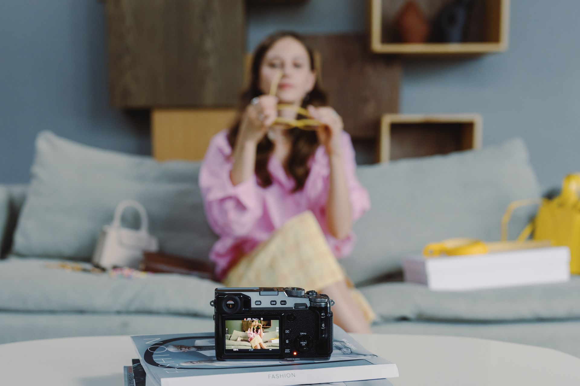 A woman is sitting on a couch taking a picture with a camera.