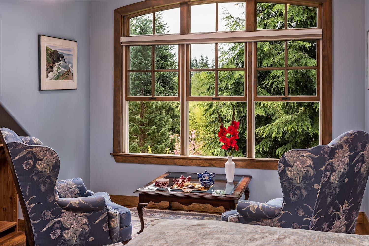 A living room with two chairs a table and a large window