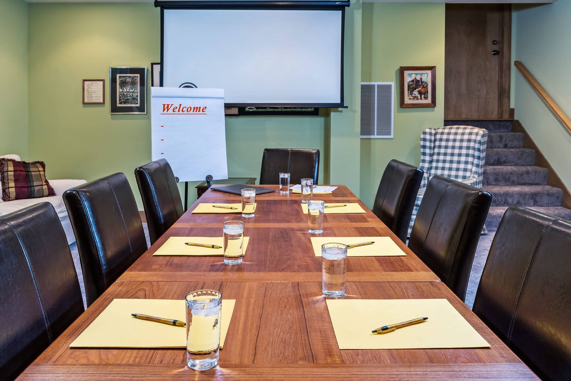 A conference room with a long table and chairs and a projector screen