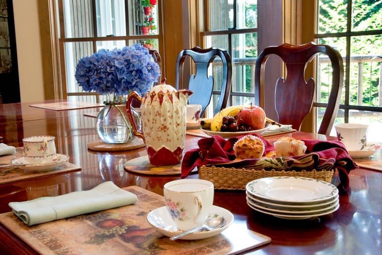 A dining room table with plates , cups , and flowers on it.