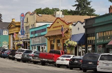 A row of cars are parked on the side of a street in a small town.