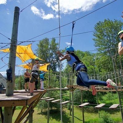A woman is flying through the air on a ropes course.