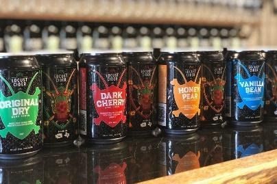 A row of cans of different flavors of beer are sitting on a table.